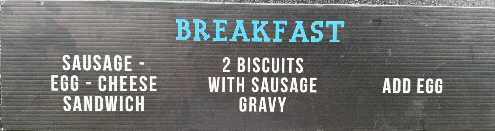 Menu sign: Breakfast — sausage, egg and cheese sandwich; two biscuits with sausage gravy; add egg